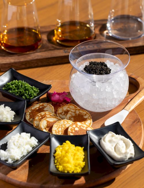 A green matcha-layer cake slice topped with a scoop of green ice cream and small green decorations on a black plate, dusted with powdered accents.