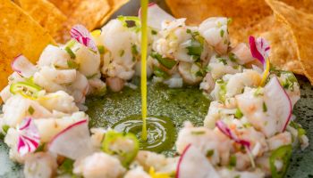 Sweet glazed chicken wings with sesame seeds and greens on a dark slate plate, crispy, caramelized and savory in appearance.