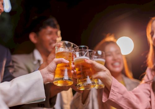 Friends clinking beer glasses in a lively night out, cheers all around at a social gathering.